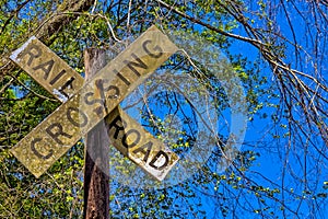 Dirty rail road crossing sign on wooden post