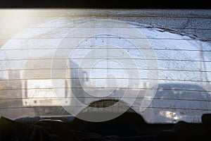 Dirty rear window of a car, view from the passenger compartment to the roadway, front and background blurred with bokeh effect