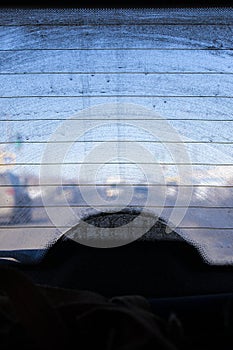 Dirty rear window of a car, view from the passenger compartment to the roadway, front and background blurred with bokeh effect