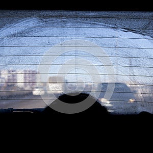 Dirty rear window of a car, view from the passenger compartment to the roadway, front and background blurred with bokeh effect