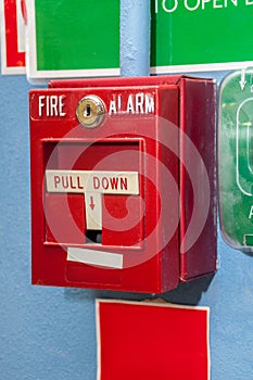 Dirty red fire alarm box with signs on the wall