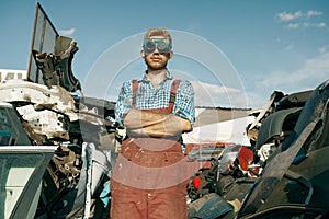 Dirty repairman in welding glasses on car junkyard