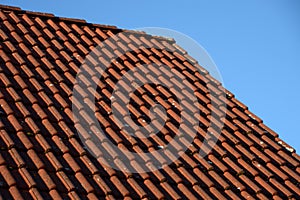 Dirty roof top lit by sun, red old dirty roof tiles in front of blue sky