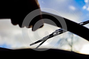 Dirty scratched car windshield with wiper through blurred steering wheel with driver`s hand on blurred background