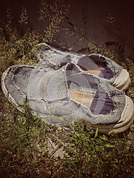 DIRTY AND SHARED OLD SHOES IN THE MIDDLE OF GRASS