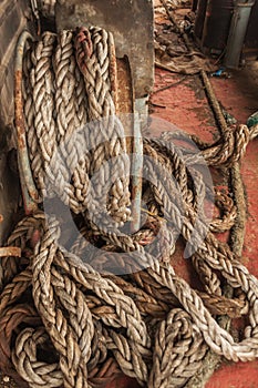 Dirty ship's rope uncoiled lying among the debris on board the shipwrecked ship. View from the ship.