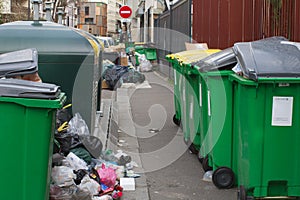 dirty sidewalks bursting with recycling containers and rubbish plastic bags