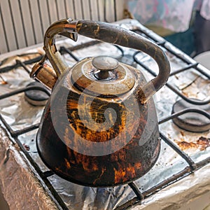 Dirty smoked kettle stands on a gas stove