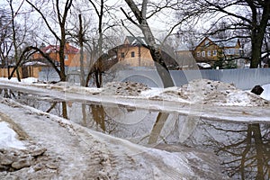 Dirty snow and puddles on the road. Gloomy spring countryside landscape