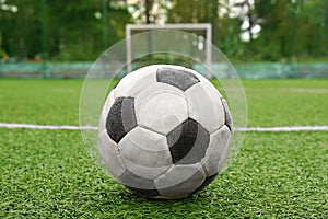 Dirty soccer ball on green football field, closeup