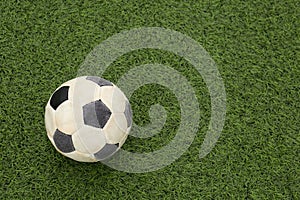 Dirty soccer ball on green football field, top view. Space for text