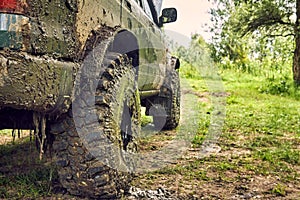 Dirty SUV is standing on the lawn after an off-road race, covered in slush