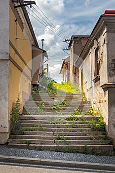 dirty unmaintained side street with grass-covered stairs between buildings