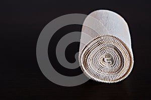 Dirty, used medical elastic bandage on a dark background. Twisted into a roll. Concept of medicine. Close-up. Place for