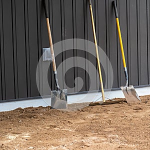 Shovels and rake lean against a wall at a construction site photo