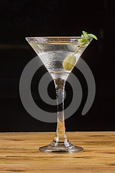 Dirty vodka martini served on  bar garnished with  green olive