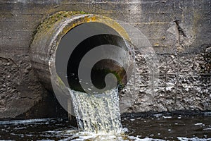 Dirty water flows from the pipe into the river, environmental pollution. Sewerage, treatment facilities