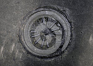 Dirty Wet Manhole Cover Surrounded by Concrete