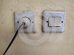 Dirty white switch and plug on the wall.