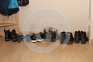 Dirty women`s men`s and children`s shoes stand in a row in the hallway