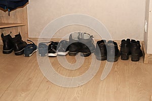 Dirty women`s men`s and children`s shoes stand in a row in the hallway