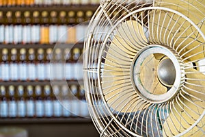 Dirtyand Old Vintage electric fan with rows of Bottles in background