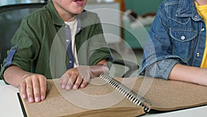 disability, close-up of blind boy moving his fingers while reading Braille book, kid studying at home
