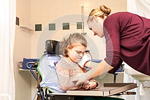 Disability a disabled child in a wheelchair being cared for by a nurse photo