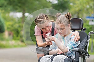 Disability a disabled child in a wheelchair relaxing outside with her sister