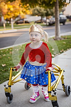 Disability photo of a cute little disabled girl walking with a special walker