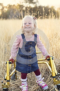 Disability photo of a cute little disabled girl walking with a special walker