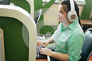 Disability young blind person happy woman in headphone typing on computer keyboard working in creative workplace office