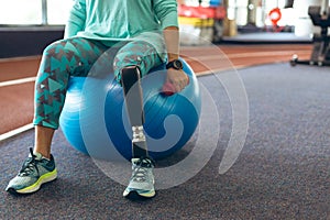 Disabled active senior woman exercising with dumbbell while sitting on exercise ball