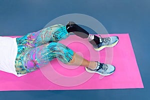 Disabled active senior woman exercising on exercising mat in sports center