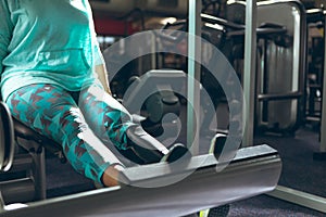 Disabled active senior woman exercising with leg press machine in fitness studio