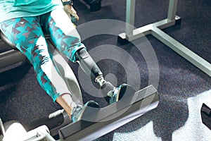 Disabled active senior woman exercising with leg press machine in fitness studio