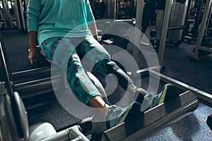 Disabled active senior woman exercising with leg press machine in fitness studio