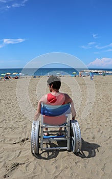 Disabled adult looks at the sea from a wheelchair