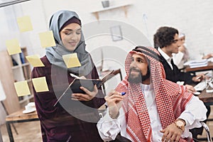 Disabled arab man in wheelchair working in office. Man is writing notes on glass board.