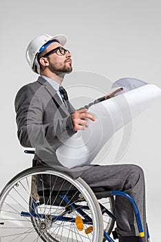 Disabled architect in wheelchair holding blueprint