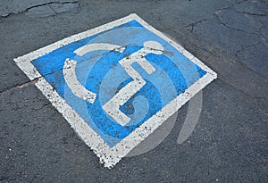 Disabled parking sign painted on asphalt.