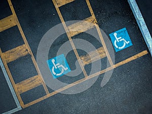 Disabled blue parking sign painted on dark asphalt. Empty handicapped spaces on black