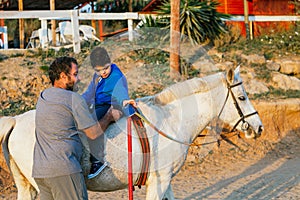 Disabled boy doing mobility exercise during an equine therapy session
