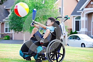 Disabled boy hitting ball with bat at park