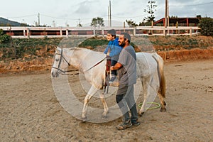 Disabled boy riding a horse during a session of physiotherapy