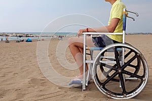 Disabled boy in a wheelchair looks at the sea