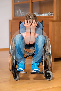 Disabled boy in wheelchair is sad