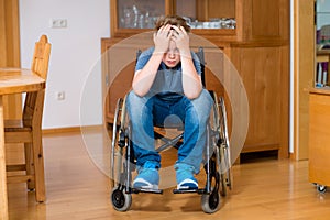 Disabled boy in wheelchair is sad