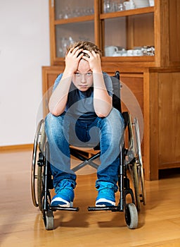 Disabled boy in wheelchair is sad