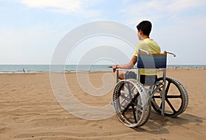 Disabled boy in the wheelchair on the sandy beach